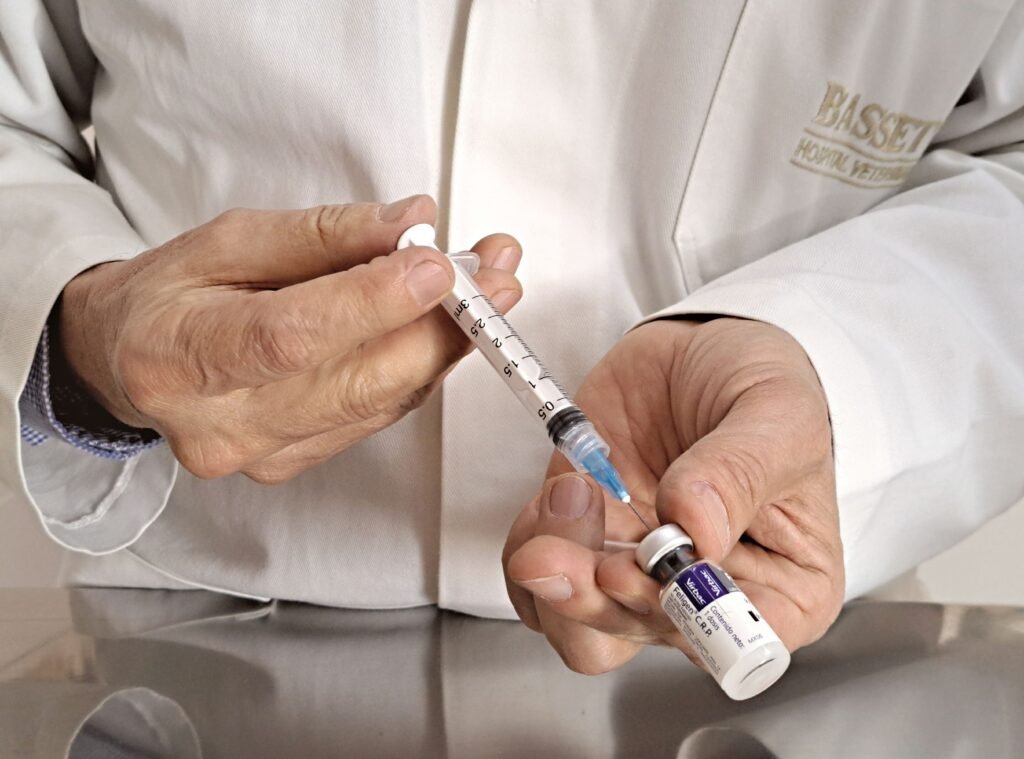 Veterinarian preparing a syringe with vaccine from a vial in a medical setting.